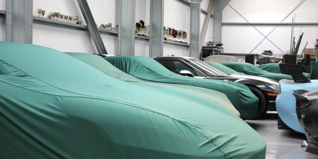 panoramic image of vehicles housed at topcats racing workshop safely stored with car covers